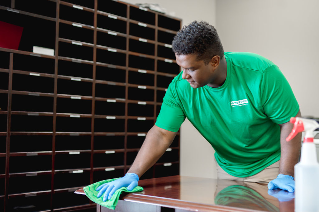 Professional cleaner cleaning mailroom desk