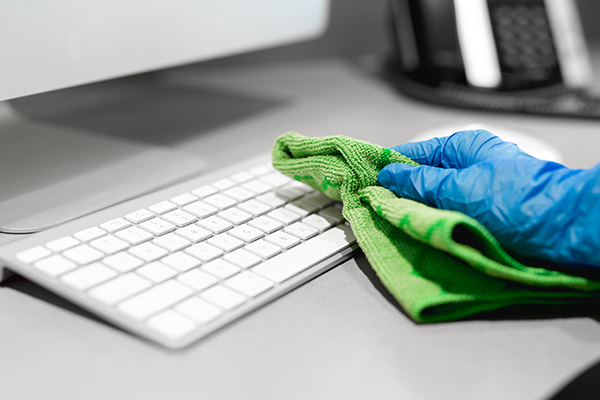 Janitor cleaning office desk keyboard