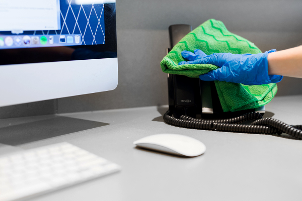 Commercial cleaning office professional wiping down a desk phone
