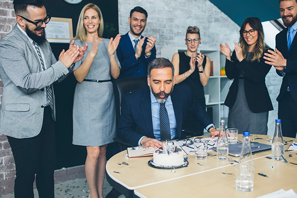 Office party celebration with employee blowing candles