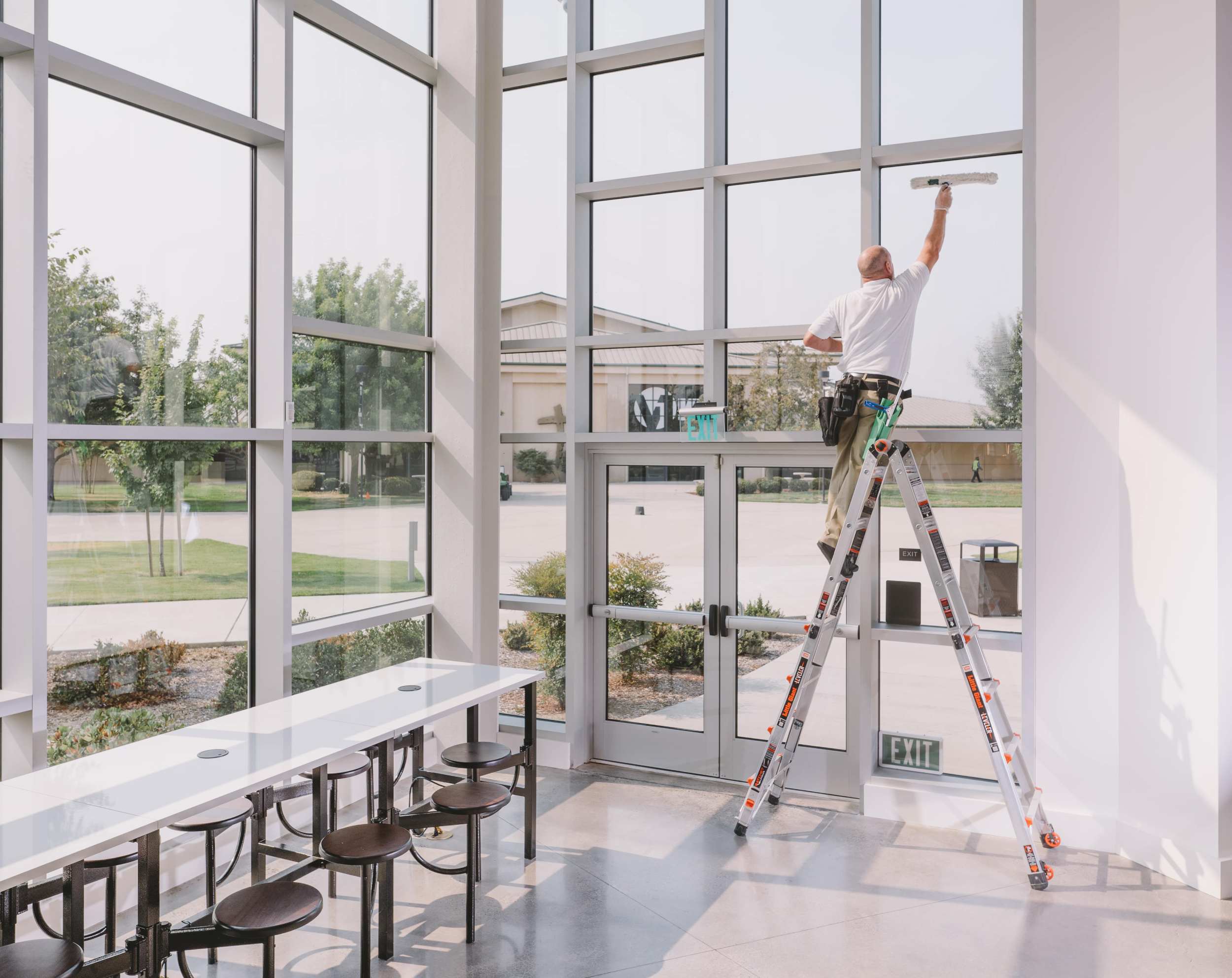professional commercial cleaner cleaning office lobby window