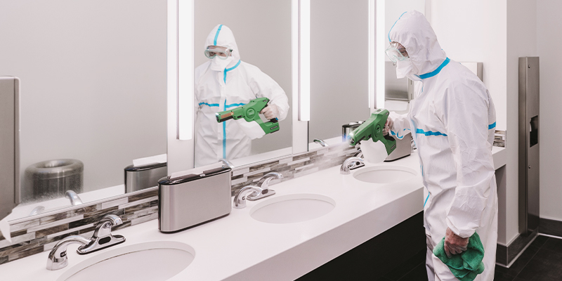 professional cleaner in restroom following the New Normal Office Cleaning Schedule