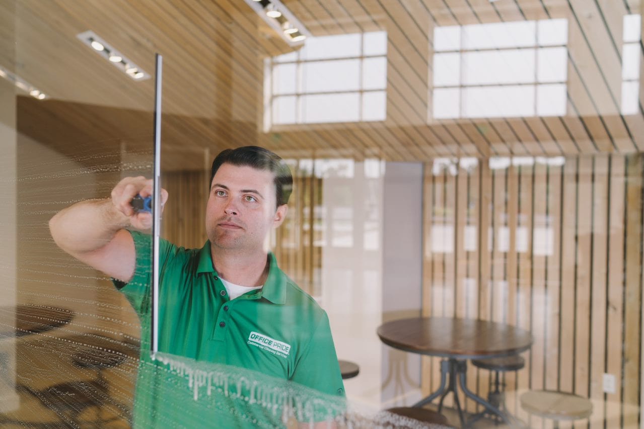 professional commercial cleaner cleaning a window for a business owner who has outsourced their cleaning needs