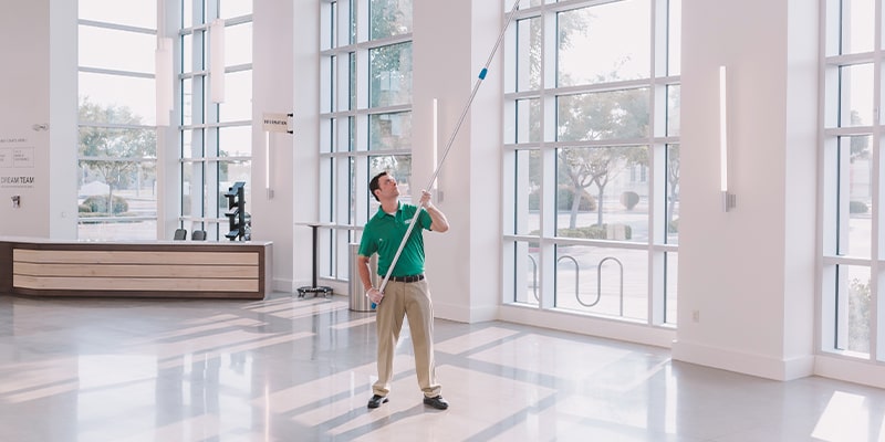 cleaning professional cleaning the indoor windows high above the lobby floor while following the customized cleaning checklist for the client during the summertime