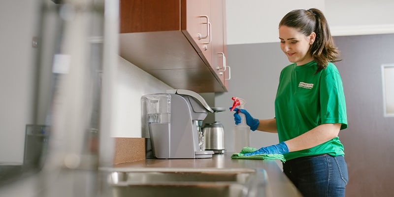 professional commercial cleaner cleaning a countertop as part of the checklist